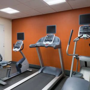 An exercise bicycle next to a treadmill and an elliptical machine in the Hampton Inn Manhattan - Madison Square Garden exercise room.