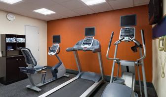 An exercise bicycle next to a treadmill and an elliptical machine in the Hampton Inn Manhattan - Madison Square Garden exercise room.