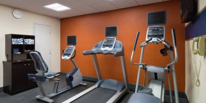 An exercise bicycle next to a treadmill and an elliptical machine in the Hampton Inn Manhattan - Madison Square Garden exercise room.