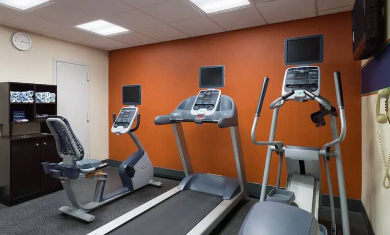 An exercise bicycle next to a treadmill and an elliptical machine in the Hampton Inn Manhattan - Madison Square Garden exercise room.