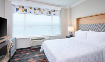 Double bed guest room in Holiday Inn & Suites Oakville At Bronte, with large window and bedside lamp.