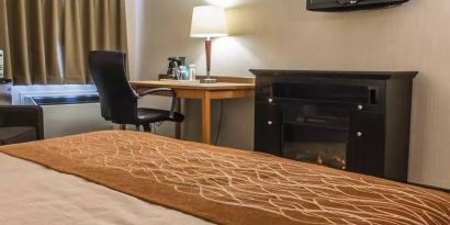 Guest room workspace in Comfort Inn Brandon, with a cozy fireplace beside the desk and chair.