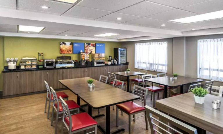 The hotel breakfast area has a hard floor, large windows, and tables for four to six diners.