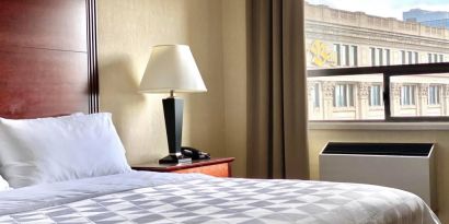 Guest room in Holiday Inn Winnipeg Downtown, with bedside lamp and window.