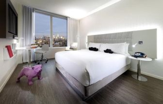 The Innside By Melia New York Nomad’s king room (city view), with large bed, TV, and the eponymous urban vista through the window.