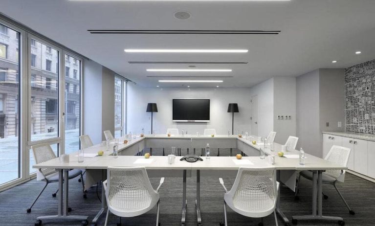 Meeting room with four long tables arranged in a square, large TV, and seating for ten attendees.