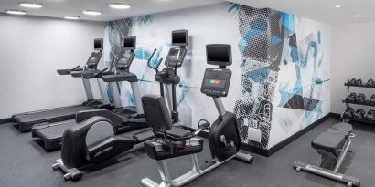 The hotel exercise center, fitted with rack of weights, bench, and multiple exercise machines.