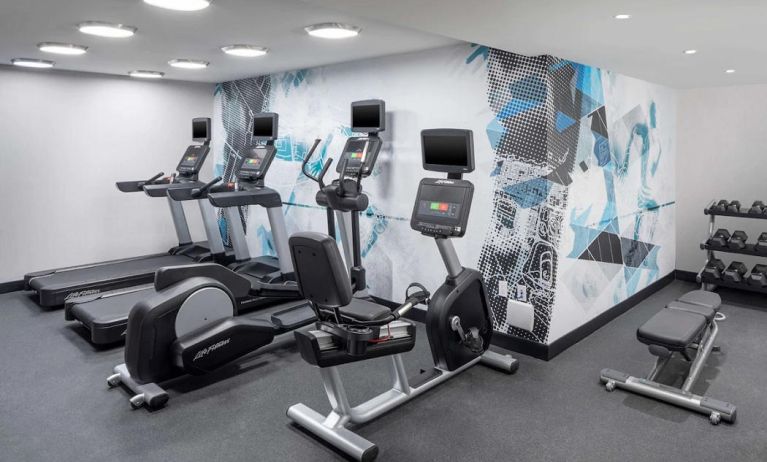 The hotel exercise center, fitted with rack of weights, bench, and multiple exercise machines.