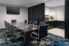 Hotel meeting room, with ten leather chairs surrounding a long table, and coffee-making facilities.