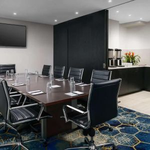 Hotel meeting room, with ten leather chairs surrounding a long table, and coffee-making facilities.