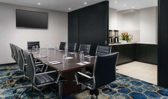 Hotel meeting room, with ten leather chairs surrounding a long table, and coffee-making facilities.