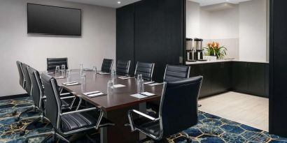 Hotel meeting room, with ten leather chairs surrounding a long table, and coffee-making facilities.