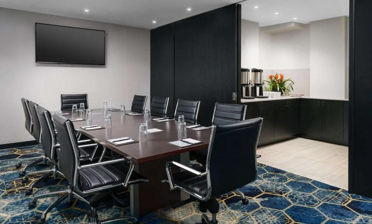 Hotel meeting room, with ten leather chairs surrounding a long table, and coffee-making facilities.