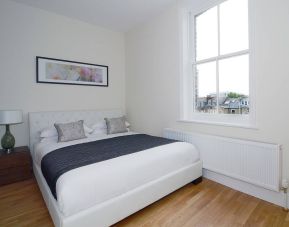 Hammersmith One’s bedroom, with double bed, bedside lamp, and nearby window.