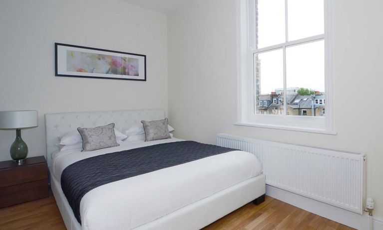 Hammersmith One’s bedroom, with double bed, bedside lamp, and nearby window.