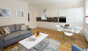 Wider view of the lounge and kitchen area, including sofa, table, and chairs.