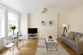 Lounge with sofa, coffee table and chairs, window, and widescreen television.