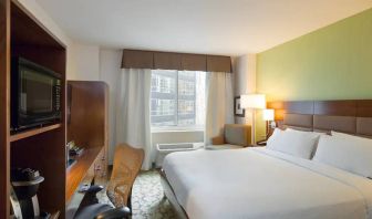 Hilton Garden Inn Midtown East guest room featuring large bed, big windows, and workspace chair and desk.