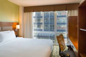 A Hilton Garden Inn Midtown East guest room with king-sized bed and floor-to-ceiling windows.