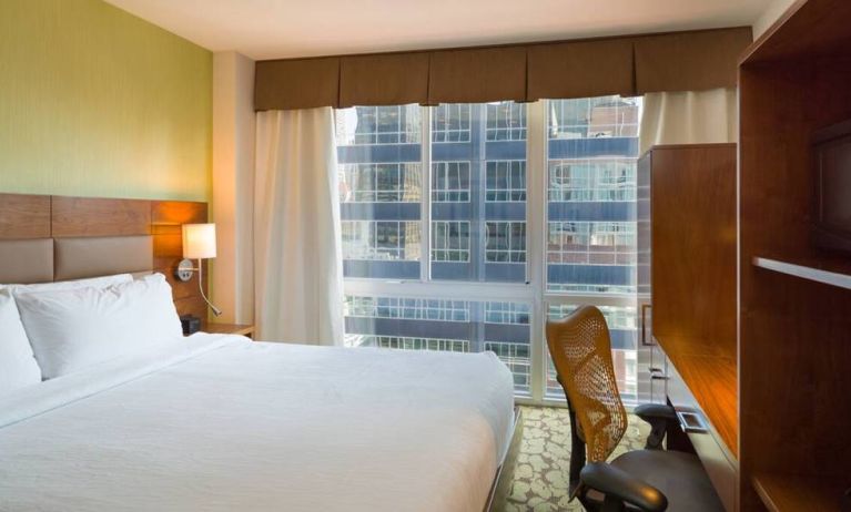 A Hilton Garden Inn Midtown East guest room with king-sized bed and floor-to-ceiling windows.