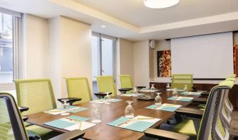 A meeting room in the Hilton Garden Inn Midtown East, with long wooden table and space for ten attendees.