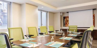 A meeting room in the Hilton Garden Inn Midtown East, with long wooden table and space for ten attendees.