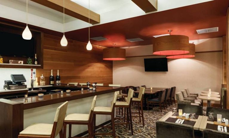 The Hilton Garden Inn Midtown East’s restaurant and bar, with tall bar stools, and tables for dining.