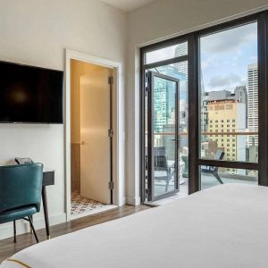 Guest room in The Draper, Ascend Hotel Collection, with TV and workspace desk and chair, plus city views.