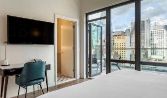 Guest room in The Draper, Ascend Hotel Collection, with TV and workspace desk and chair, plus city views.