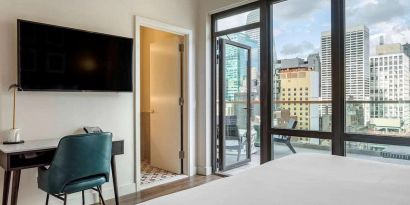 Guest room in The Draper, Ascend Hotel Collection, with TV and workspace desk and chair, plus city views.