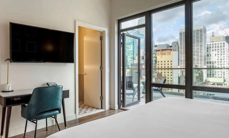 Guest room in The Draper, Ascend Hotel Collection, with TV and workspace desk and chair, plus city views.