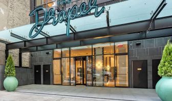 The hotel’s exterior, with The Draper, Ascend Hotel Collection’s name, awning, and large potted plants.