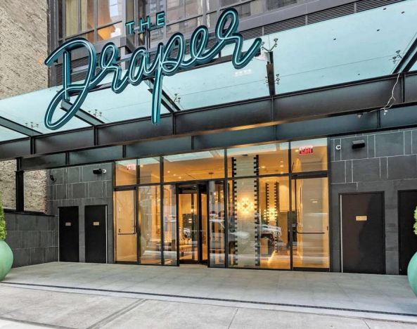 The hotel’s exterior, with The Draper, Ascend Hotel Collection’s name, awning, and large potted plants.