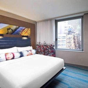 Double bed guest room in the Aloft Manhattan Downtown - Financial District, with art on the wall and large window.