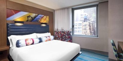 Double bed guest room in the Aloft Manhattan Downtown - Financial District, with art on the wall and large window.