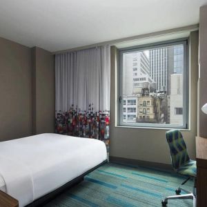 A single bed guest room in the Aloft Manhattan Downtown - Financial District, with TV and workspace desk and chair.