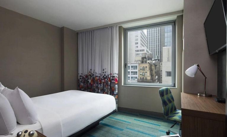 A single bed guest room in the Aloft Manhattan Downtown - Financial District, with TV and workspace desk and chair.