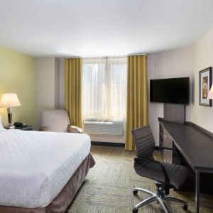 Double bed guest room in the Candlewood Suites Times Square, with workspace nearby and large window.