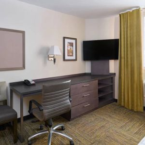 Workspace in a Candlewood Suites Times Square guest room, with desk, chair, TV, and window.