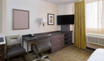 Workspace in a Candlewood Suites Times Square guest room, with desk, chair, TV, and window.