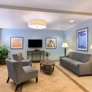 The lounge in the Candlewood Suites Times Square lobby, with comfy chairs, sofa, table, and TV.