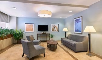 The lounge in the Candlewood Suites Times Square lobby, with comfy chairs, sofa, table, and TV.