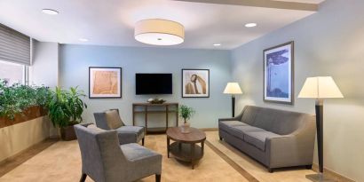 The lounge in the Candlewood Suites Times Square lobby, with comfy chairs, sofa, table, and TV.