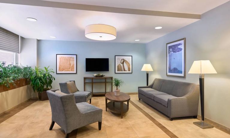 The lounge in the Candlewood Suites Times Square lobby, with comfy chairs, sofa, table, and TV.