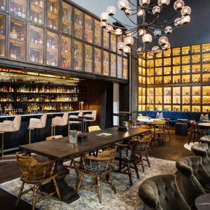 The bar and lounge of Hyatt Union Square New York, with hard floor, bar stools, and range of table sizes.