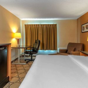 Comfort Inn Sault Ste. Marie guest room featuring large double bed, TV, and armchair.