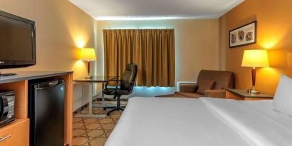 Comfort Inn Sault Ste. Marie guest room featuring large double bed, TV, and armchair.