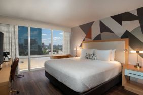 Double bed guest room in The Beeman Hotel, featuring large bed, and city view through the window.