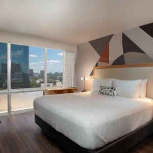 Double bed guest room in The Beeman Hotel, featuring large bed, and city view through the window.