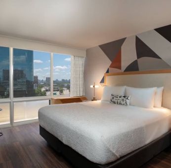 Double bed guest room in The Beeman Hotel, featuring large bed, and city view through the window.